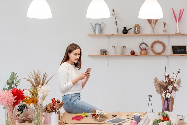 Giovane fiorista femminile che per mezzo del suo telefono cellulare