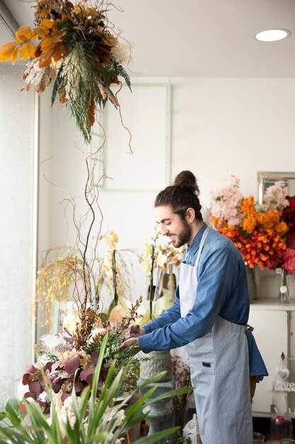 Giovane fiorista maschio sorridente che prende cura dei fiori nel mazzo