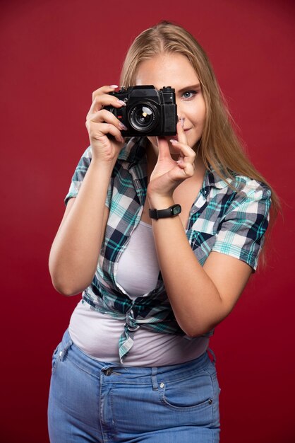 Giovane fotografia bionda in possesso di una macchina fotografica professionale e servizio fotografico in modo professionale.