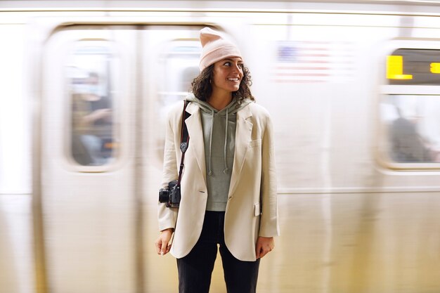 Giovane fotografo femminile alla moda che esplora la metropolitana in città