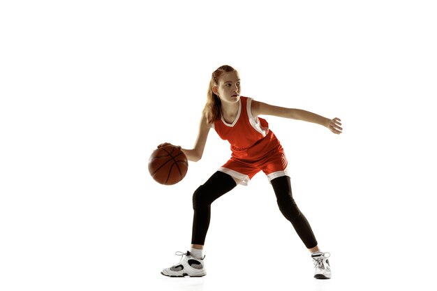 Giovane giocatore di basket femminile in azione, movimento in esecuzione isolato sul muro bianco