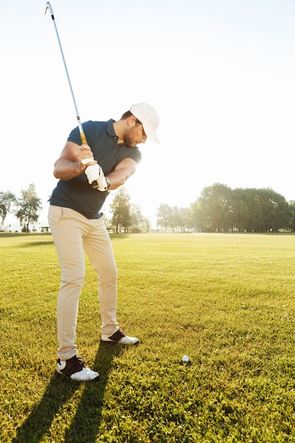 Giovane giocatore di golf maschio che colpisce palla con un club