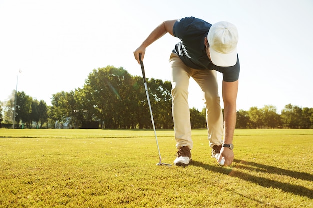 Giovane giocatore di golf maschio che dispone la palla da golf su un T