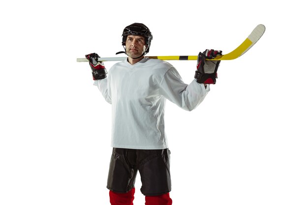 Giovane giocatore di hockey maschio con il bastone sul campo da ghiaccio e sfondo bianco.