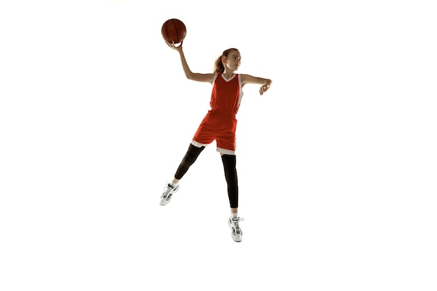 Giovane giocatore di pallacanestro femminile caucasico in azione, movimento nel salto isolato su priorità bassa bianca. Redhair ragazza sportiva. Concetto di sport, movimento, energia e stile di vita dinamico e sano. Formazione.