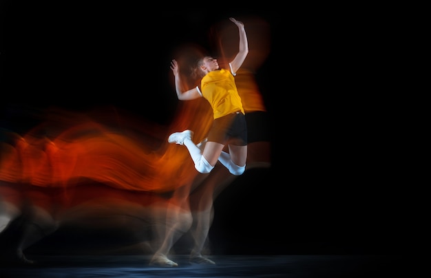 Giovane giocatore di pallavolo femminile in studio nero in luce mista.