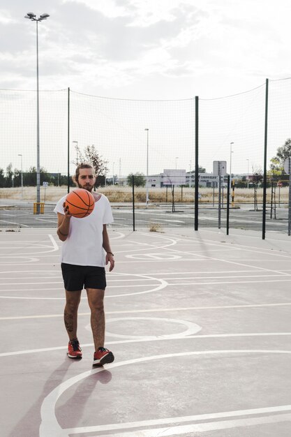 Giovane giocatore maschio con pallacanestro in tribunale