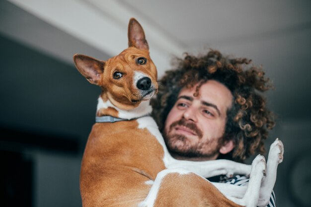 Giovane hipster alla moda con tatuaggi capelli ricci pazzi coccola il suo piccolo migliore amico