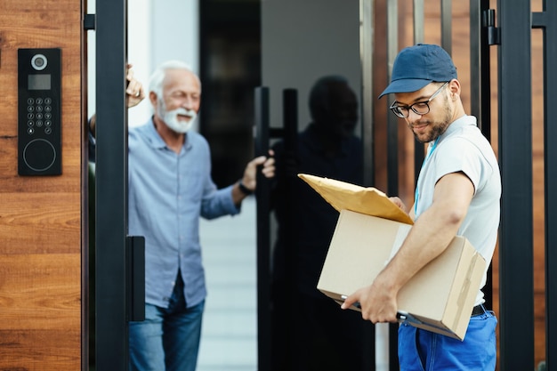 Giovane impiegato delle poste che effettua la consegna a domicilio a un cliente senior