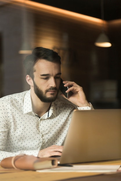 Giovane imprenditore dell'angolo alto che parla sopra il telefono