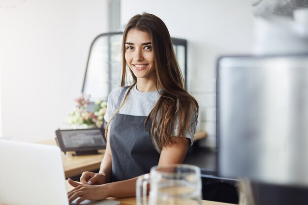 Giovane imprenditrice che gestisce la sua prima attività in una caffetteria di recente apertura