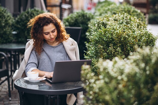 Giovane imprenditrice lavorando su un computer fuori dal bar