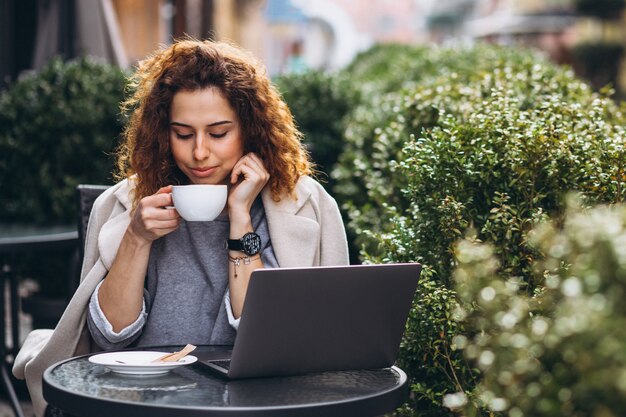 Giovane imprenditrice lavorando su un computer fuori dal bar