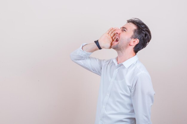 Giovane in camicia bianca che grida o annuncia qualcosa e sembra eccitato