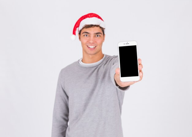 Giovane in cappello di natale che mostra smartphone