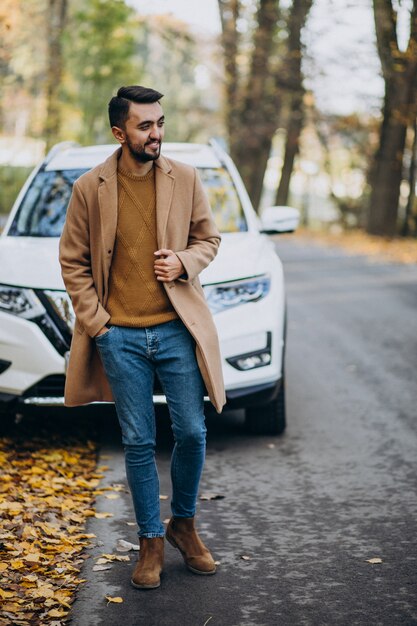 Giovane in cappotto da portare della foresta in macchina