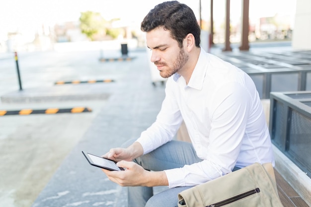 Giovane in formale che legge il suo romanzo preferito usando un e-reader