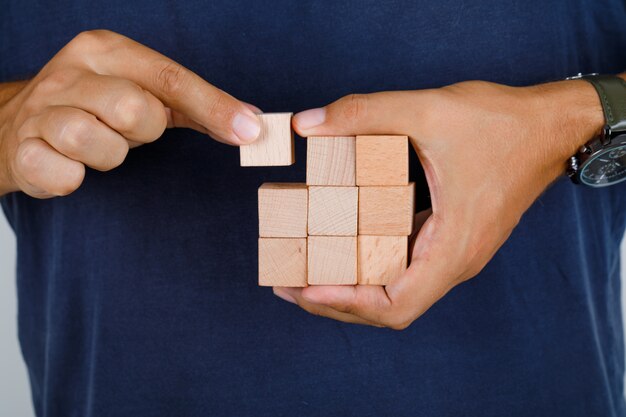 Giovane in maglietta blu scuro che tiene uno dei blocchi di legno, vista frontale.