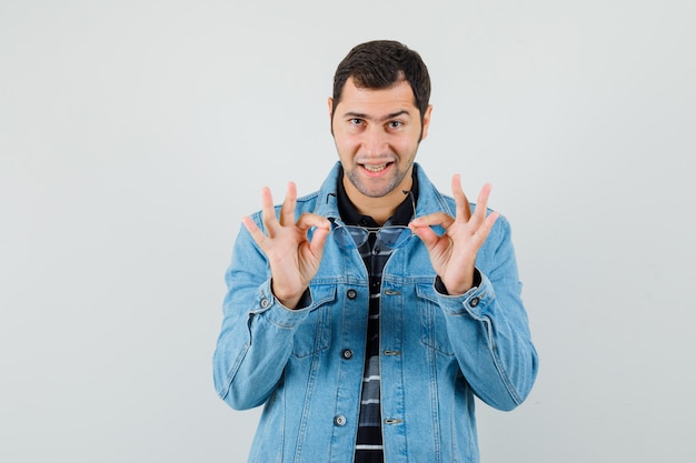 Giovane in t-shirt, giacca che mostra il gesto giusto e alla ricerca di contenuto