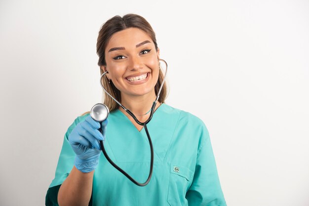 Giovane infermiera femminile positiva con lo stetoscopio su fondo bianco