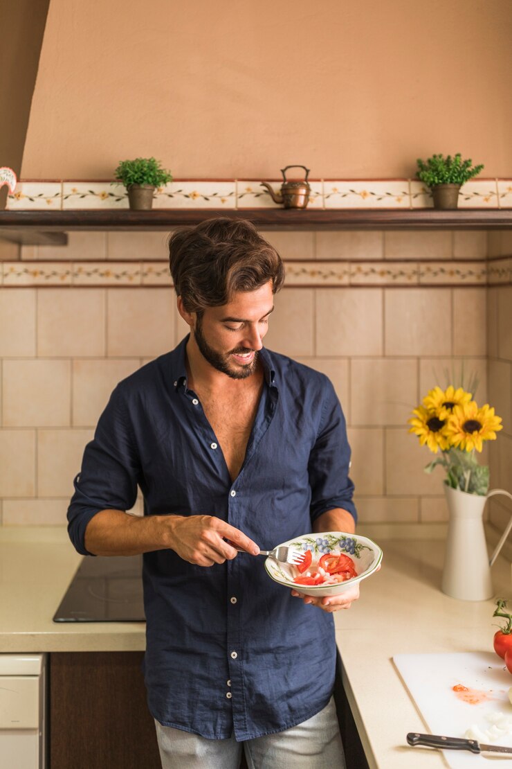 Foto gratuito giovane insalata mangiatrice di uomini sorridente con la forcella