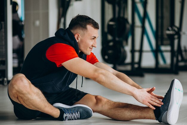 Giovane istruttore di fitness che si estende in palestra