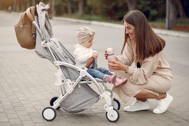 Giovane madre che cammina in un parco di autunno con il trasporto