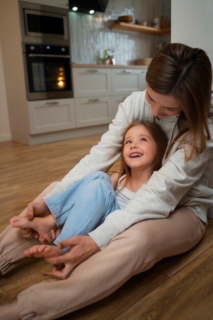 Giovane madre che fa ridere sua figlia facendole il solletico