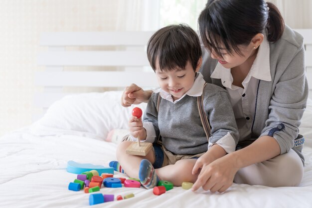 Giovane madre che gioca con il figlio adorabile nella camera da letto