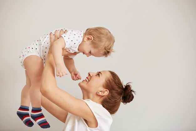 Giovane madre che gioca con il suo piccolo bambino sul letto