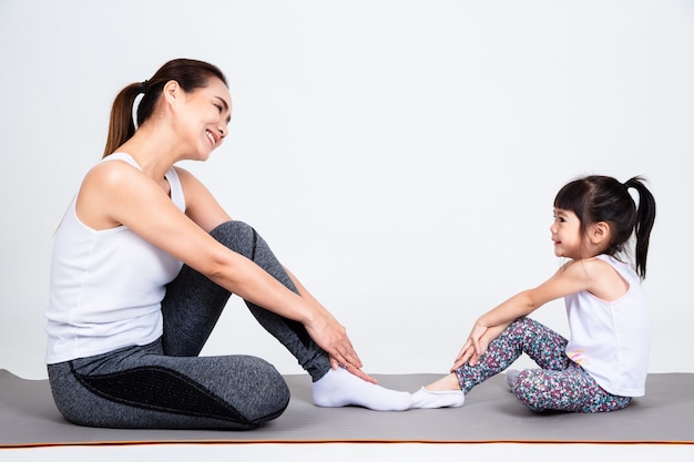 Giovane madre che prepara figlia adorabile con yoga