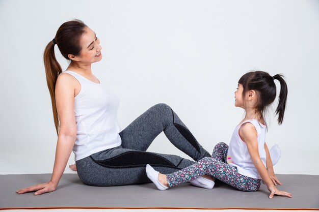 Giovane madre che prepara figlia adorabile con yoga