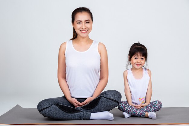 Giovane madre che prepara figlia adorabile con yoga