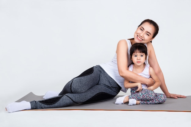 Giovane madre che prepara figlia adorabile con yoga