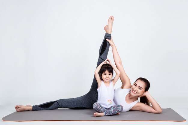 Giovane madre che prepara figlia adorabile con yoga