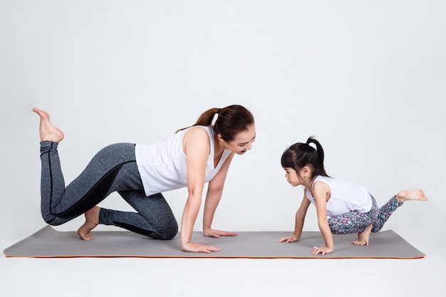 Giovane madre che prepara figlia adorabile con yoga