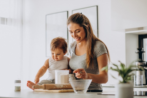 Giovane madre con il suo piccolo figlio che cucina alla cucina