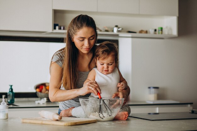 Giovane madre con il suo piccolo figlio che cucina alla cucina