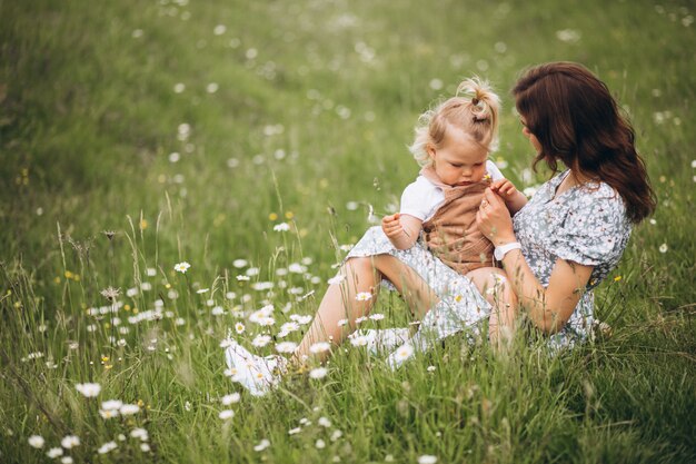 Giovane madre con la piccola figlia nel parco che si siede sull'erba