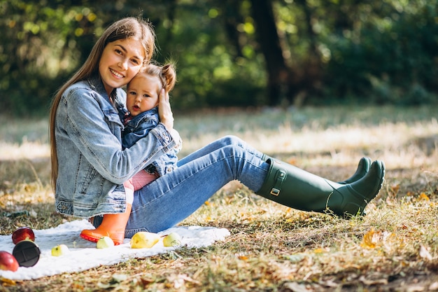 Giovane madre con la sua piccola figlia in un parco di autunno che ha picnic