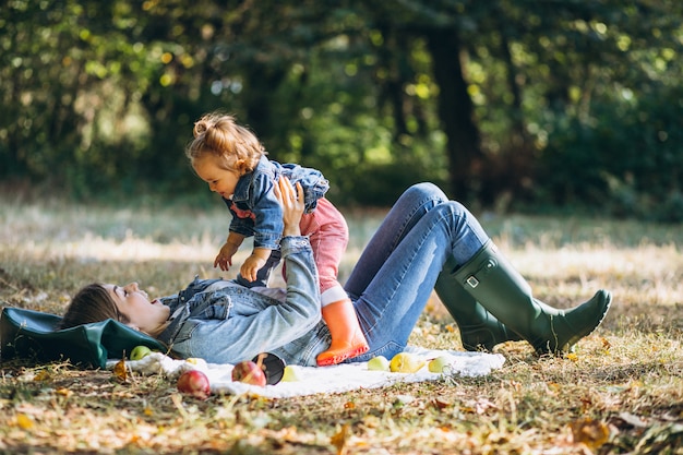 Giovane madre con la sua piccola figlia in un parco di autunno che ha picnic