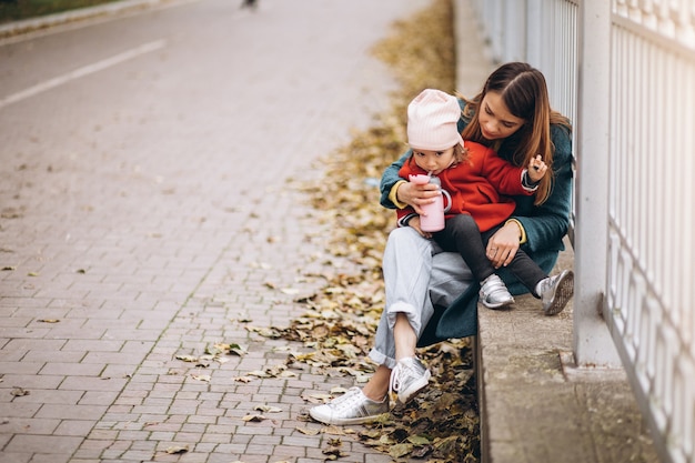 Giovane madre con la sua piccola figlia in un parco in autunno