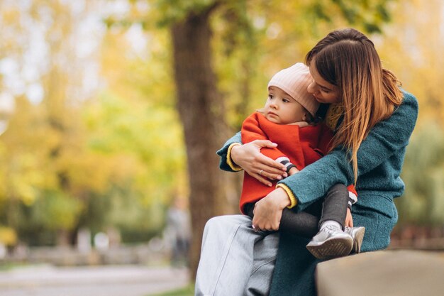 Giovane madre con la sua piccola figlia in un parco in autunno