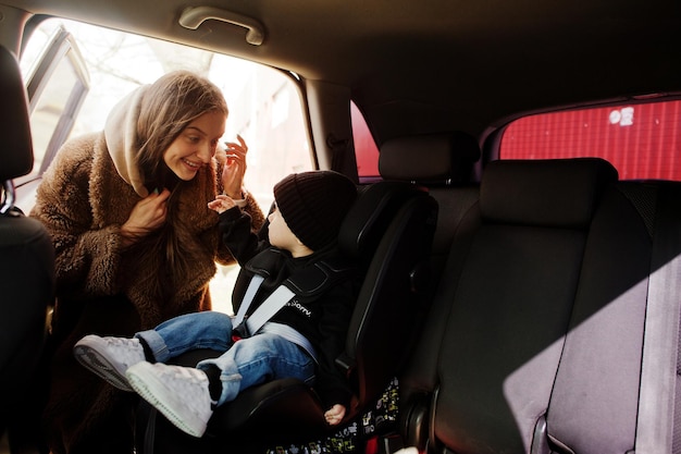 Giovane madre e bambino in auto Seggiolino per bambini sulla sedia Concetto di guida sicura