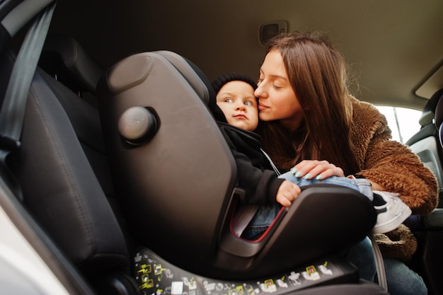 Giovane madre e bambino in auto Seggiolino per bambini sulla sedia Concetto di guida sicura