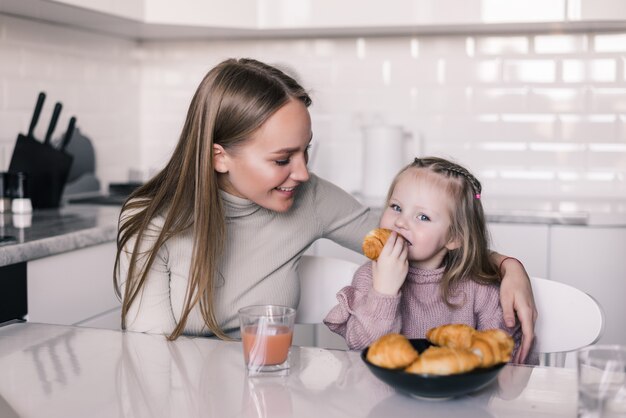 Giovane madre e figlia facendo colazione al tavolo della cucina