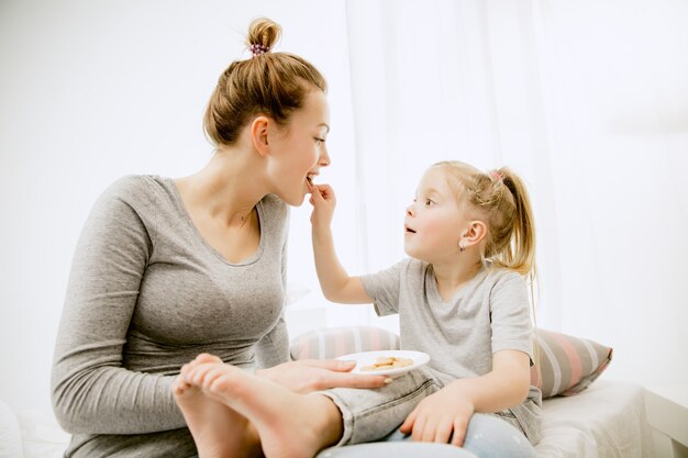 Giovane madre e la sua piccola figlia a casa al mattino pieno di sole.