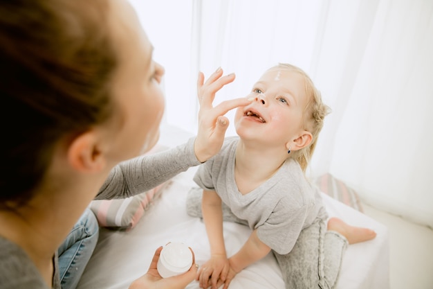 Giovane madre e la sua piccola figlia a casa al mattino pieno di sole.