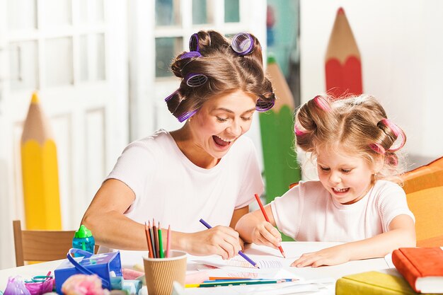 giovane madre e la sua piccola figlia di disegno con le matite a casa