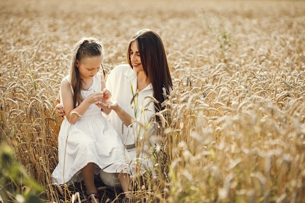 giovane madre e sua figlia in abiti bianchi al campo di grano in una giornata di sole.